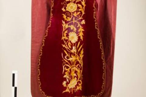 El objeto es una tela decorada en color burdeos con un patrón de flores doradas.
