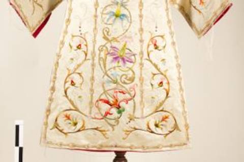 Vestido ceremonial bordado con flores de colores en un fondo claro.