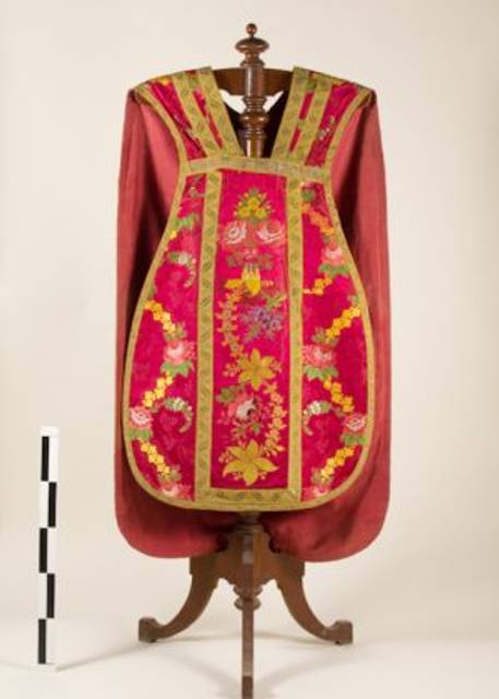 Una vestimenta ceremonial de color rojo con bordados coloridos y detalles florales.