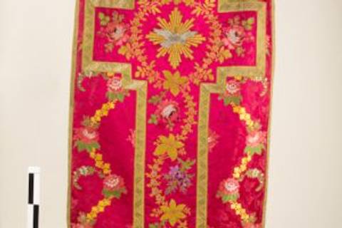 Una hermosa tela con un diseño intrincado en tonos rojos y dorados, adornada con bordados coloridos de flores y un gran motivo central.