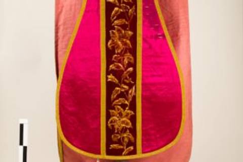 La imagen muestra un vestido tradicional con bordados coloridos y una combinación de tonos rosados y dorados.