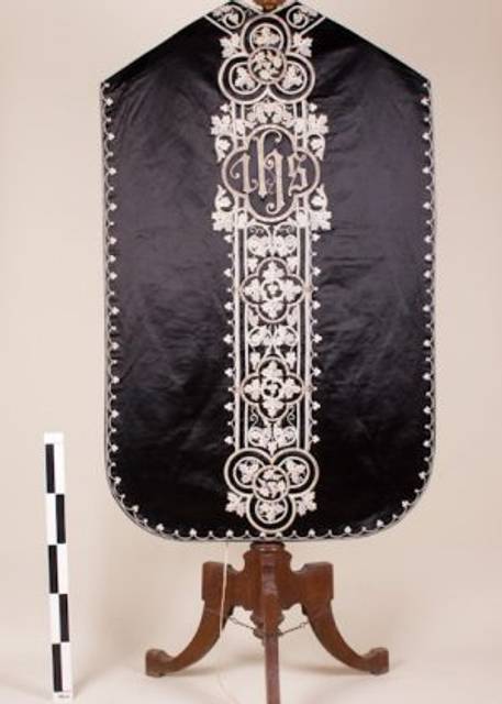 Escudo decorativo en negro con detalles blancos y una base de madera.