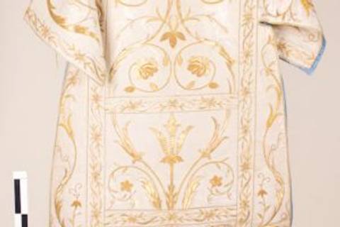 Vestimenta blanca con bordados dorados y diseño floral.