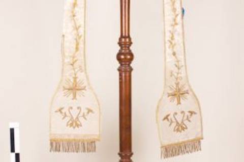 Un objeto decorativo con dos estolas colgando de un soporte de madera.