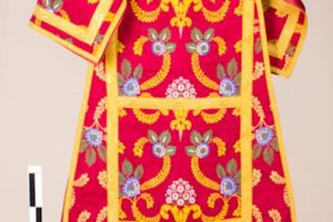 La imagen muestra una prenda de vestir tradicional con un vibrante diseño floral en tonos rojos y amarillos.