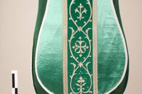 La imagen muestra un tapiz o tela decorativa de color verde, adornada con diseños florales en tonos más claros.