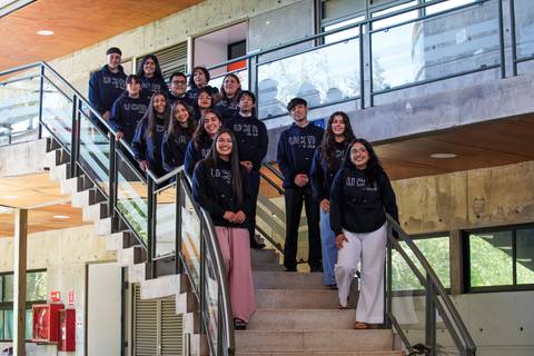 Un grupo de jóvenes sonrientes en una escalera, todos vistiendo poleras con capucha.