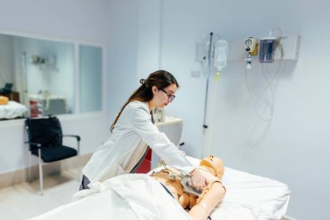 Una estudiante de medicina realiza prácticas con un maniquí en un hospital.