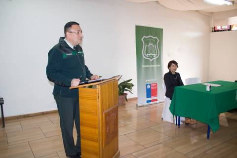 Un hombre que habla en un podio frente a una mujer sentada en una mesa verde.