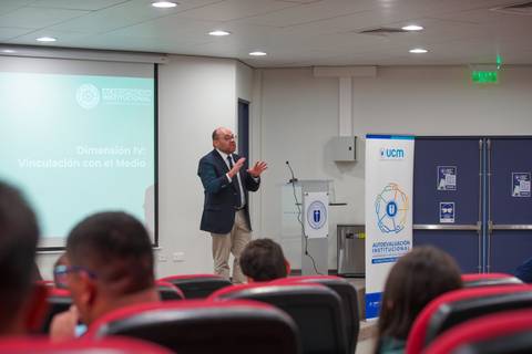 Un expositor presenta en una conferencia sobre vinculación con el medio en un auditorio.