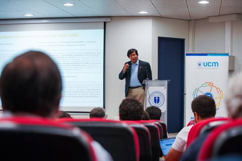 Un expositor presenta un tema ante un público atento en un auditorio.