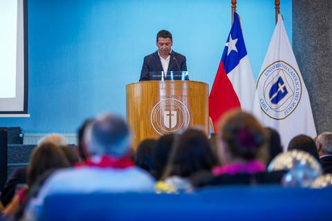 Un hombre está hablando en un evento en el aula de la Universidad Católica de Chile.