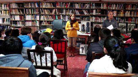 Una charla educativa en una biblioteca con un grupo de estudiantes atentos.