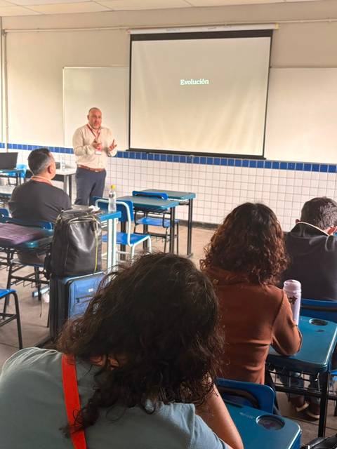 Un profesor está presentando sobre la evolución frente a un grupo de estudiantes.