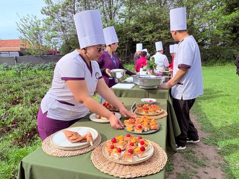 Un grupo de personas atendiendo un evento al aire libre con platos decorativos.