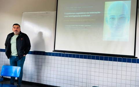 Un hombre presenta un tema sobre inteligencia artificial en una sala de clases.