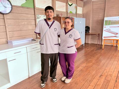 Dos jóvenes en uniformes interactuando en un aula.