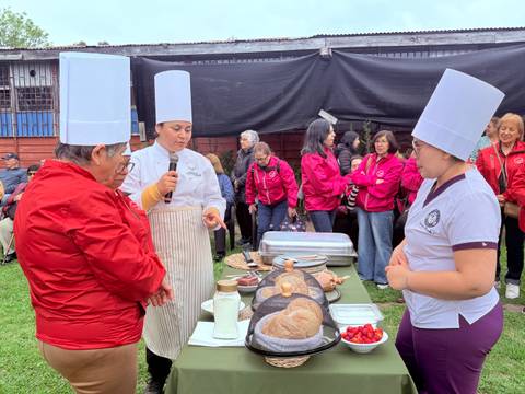 En una actividad gastronómica, tres chef presentan deliciosos panes y productos locales en un ambiente festivo.