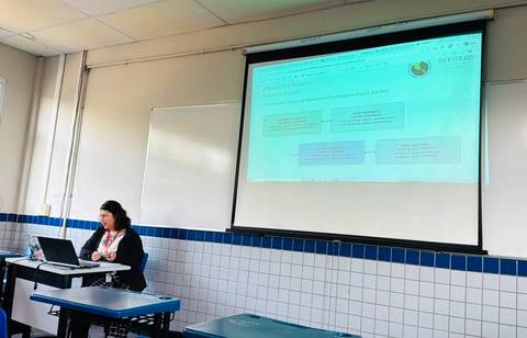 Una mujer presenta en una clase frente a una proyección de una diapositiva.