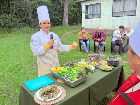Una chef presenta productos locales en un taller culinario al aire libre.
