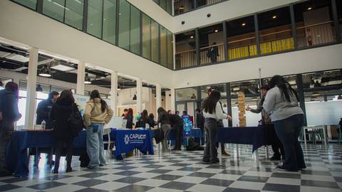 Una feria educativa con varios stands y gente interactuando en un espacio amplio.