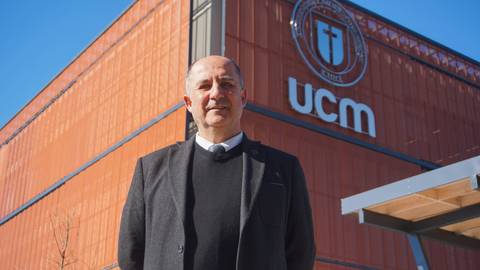 Un hombre posando frente al edificio de la UCM en un día soleado.