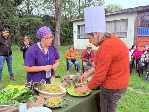 Dos mujeres preparan una ensalada en una actividad comunitaria al aire libre.