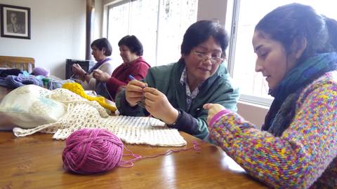 Un grupo de mujeres se reúne para tejer y compartir en un ambiente acogedor.