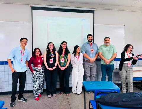 Grupo de profesionales posando en una sala de clase durante un evento académico.