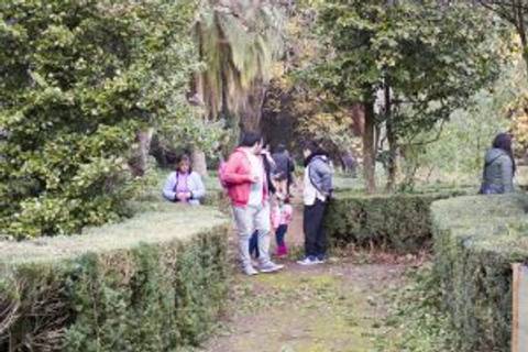 Un grupo de personas paseando en un jardín rodeado de setos.