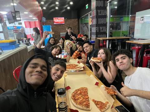 Un grupo de amigos disfrutando de pizzas en un local lleno de energía.
