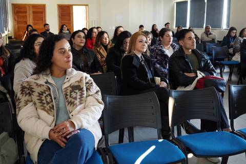 Un grupo de personas sentadas en una sala prestando atención a una presentación.