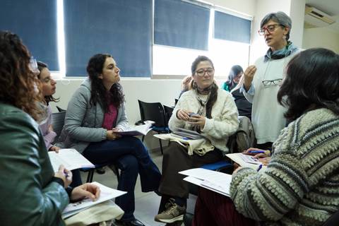 Un grupo de mujeres se encuentra en una reunión, escuchando atentamente a una expositora.