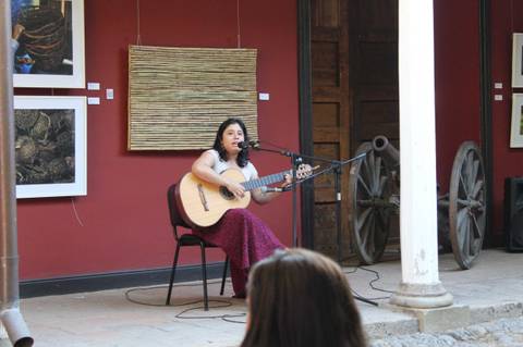 Una mujer canta y toca la guitarra en un evento cultural en un galpón.