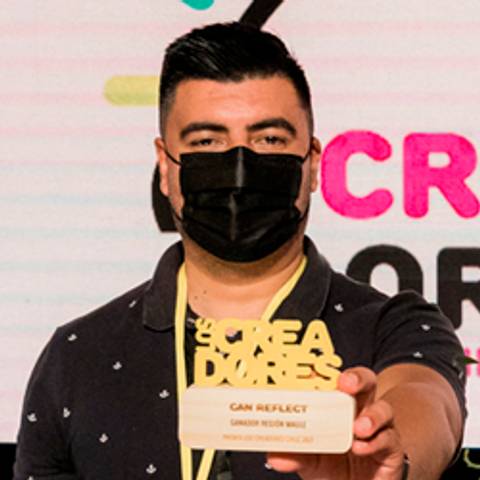 Una persona sostiene un trofeo mientras mira a la cámara en un evento.