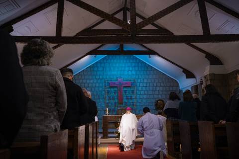 Una ceremonia religiosa en una iglesia con asistentes en oración.