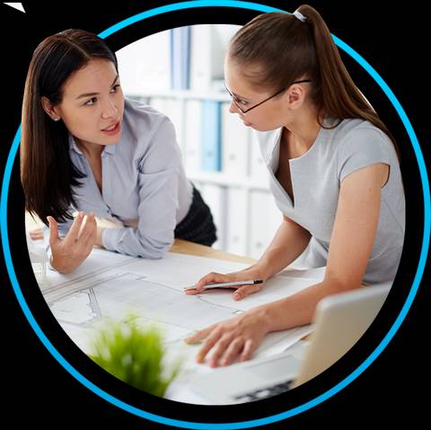 Dos mujeres dialogan sobre un plano en un entorno de oficina.