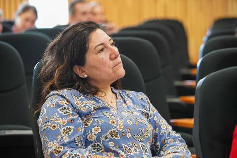 Mujer con blusa floral escuchando atentamente en una sala de clases.
