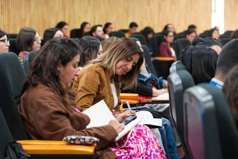 Un grupo de personas en una charla, concentradas en tomar apuntes.