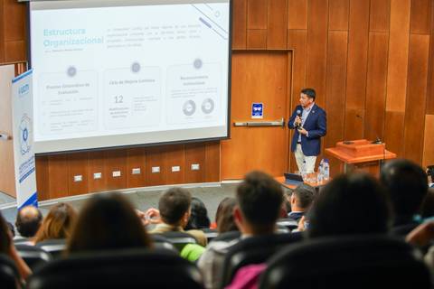 Un expositor presenta información sobre la estructura organizacional a un grupo de asistentes.