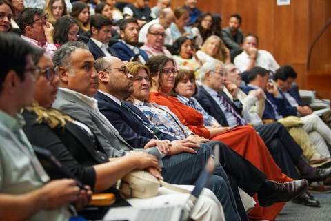 Una gran multitud de personas sentadas en un auditorio escuchando atentamente.