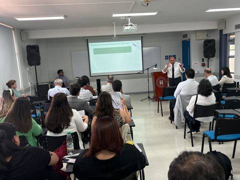 Una presentación en sala con varios asistentes escuchando atentamente.