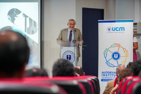 Un caballero mayor habla en una conferencia en la Universidad Católica del Maule.