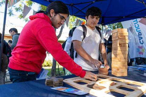 Dos jóvenes jugando con bloques de madera en una feria educativa.