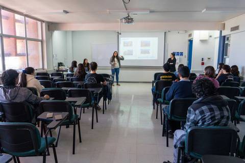 Clase en una sala con varias personas prestando atención a una presentación.