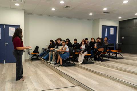 Una profesora está dando una charla a un grupo de estudiantes en un auditorio.