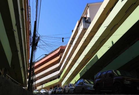 Una toma de un pasaje en un sector urbano con edificios altos y líneas eléctricas visibles.