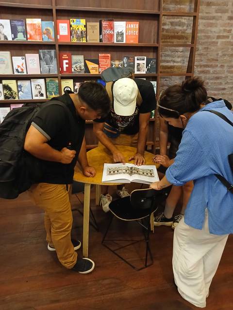 Un grupo de personas está mirando un libro en una mesa dentro de una librería.