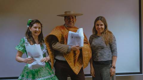 Tres personas posando en un evento cultural con trajes típicos chilenos.