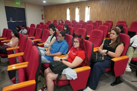 Un grupo de personas sentadas en una sala de espera con asientos rojos.
